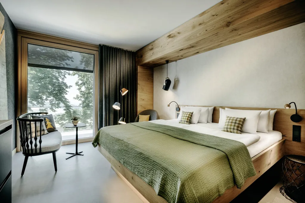Doppelbett mit grünem Bettüberwurf und Holzbalken an der Decke im Luisenhöhe Gesundheitsresort
