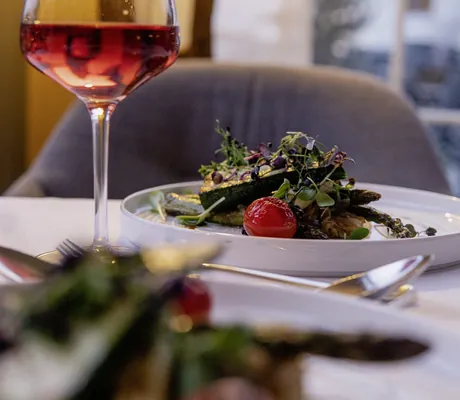 Gemüsegericht auf weißem Teller und Glas Rosé im Panoramahotel Oberjoch