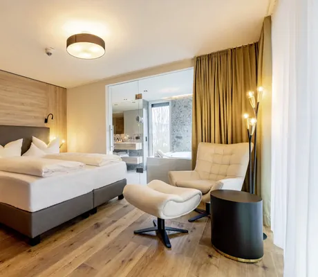 Doppelzimmer im Pfalzblick Wald Spa Resort mit weißem Sessel mit Fußteil