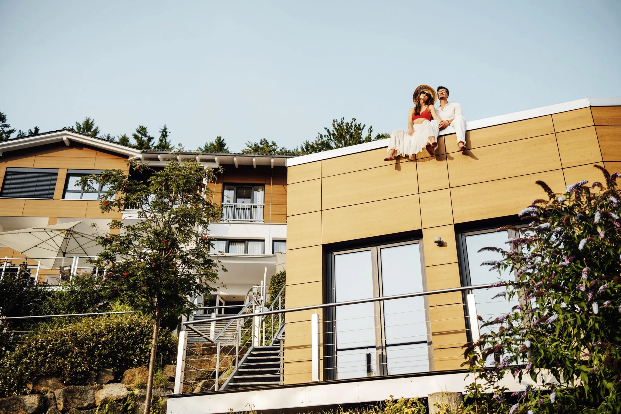 Paar mit Sonnenbrille und Hut sitzt auf dem Dach des Anbaus im Thula Wellnesshotel