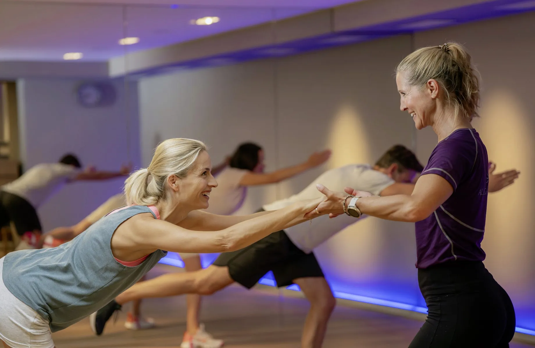 blonde Trainerin zieht blonde Frau an den Händen und stretcht sie im Hotel Allgäu Sonne