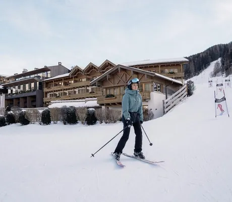 Frau in Skioutfit fährt Ski auf der Piste vor der Riederalm
