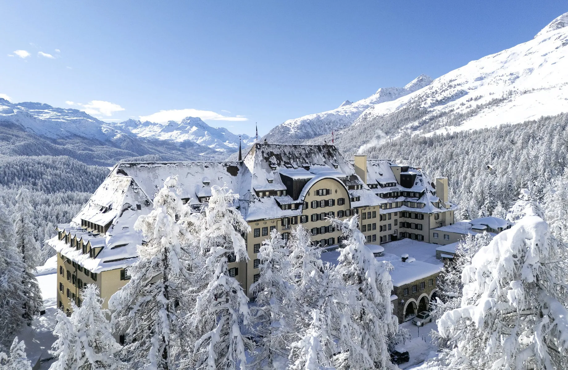 Außenaufnahme Suvretta House von oben im tiefen Schnee mit Blick in die Berge