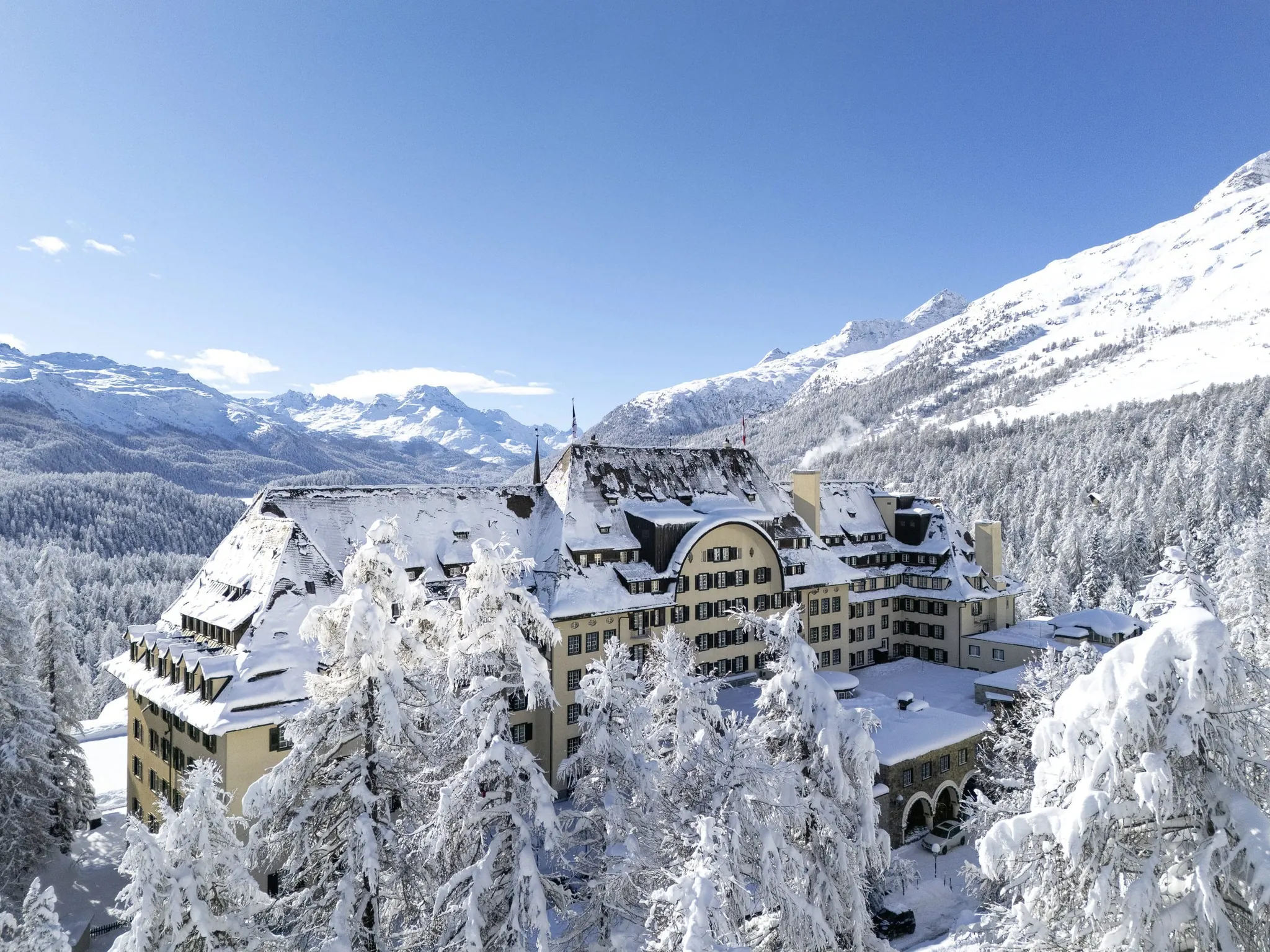 Außenaufnahme Suvretta House von oben im tiefen Schnee mit Blick in die Berge