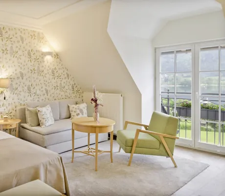 Dachzimmer im Waldhof Fuschlsee mit heller Vogeltapete und grünem Sessel