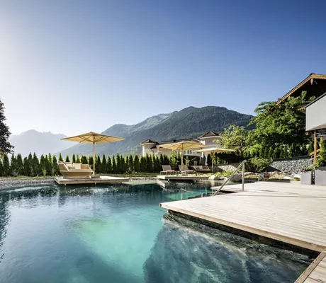 Naturpool im Wanderhotel Gassner mit Holzsteg und gehissten Flaggen