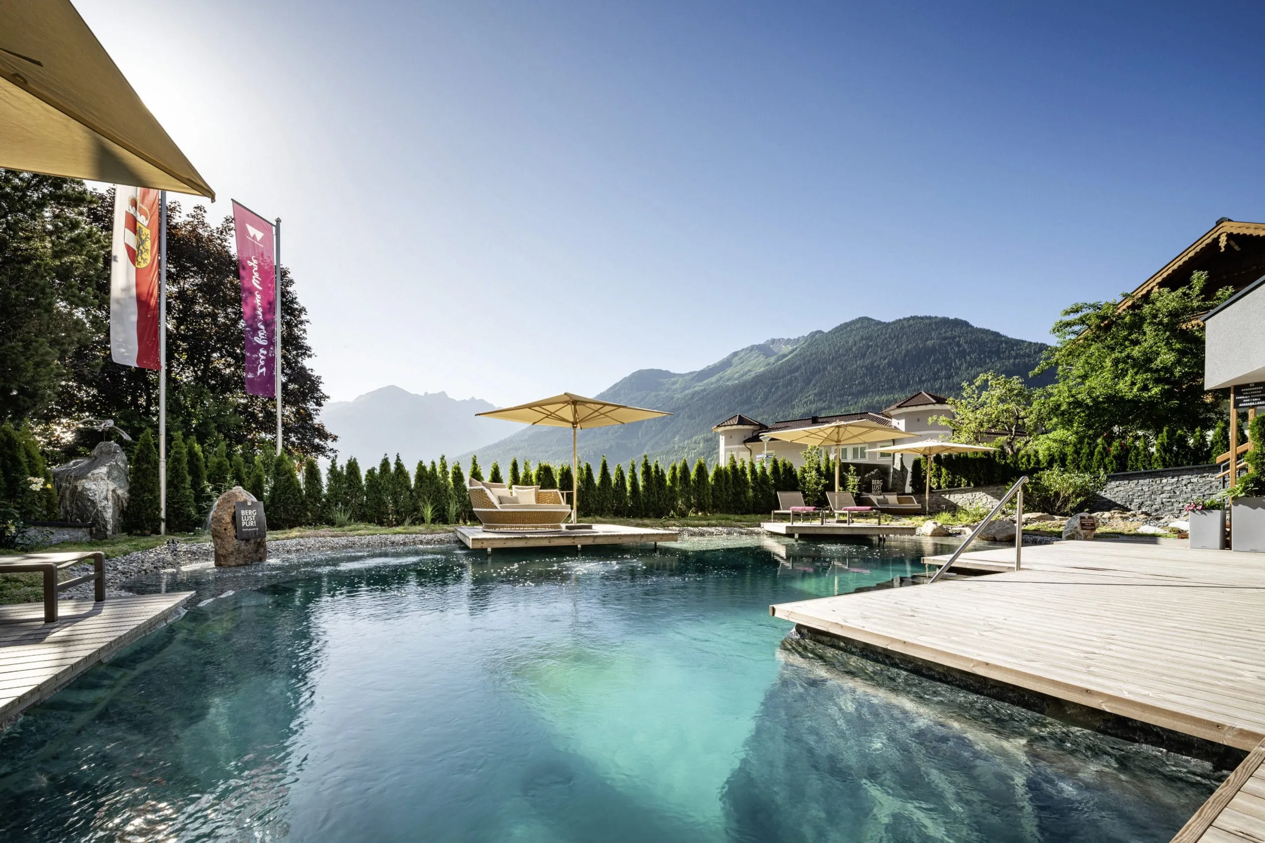 Naturpool im Wanderhotel Gassner mit Holzsteg und gehissten Flaggen