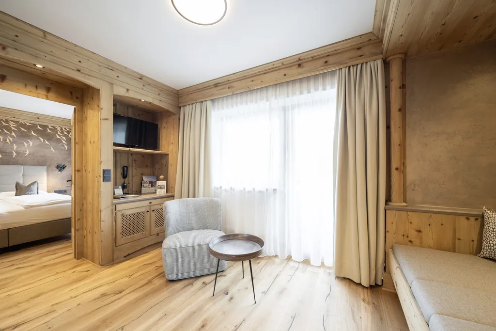 Wohnbereich im Wanderhotel Gassner mit Holzsitzecke und Blick ins Schlafzimmer