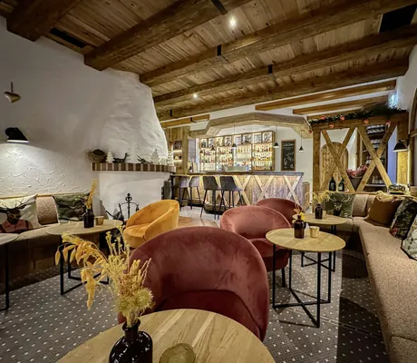gemütliche Bar mit Holzdecke und weißem Kaminofen im Yachthotel Chiemsee