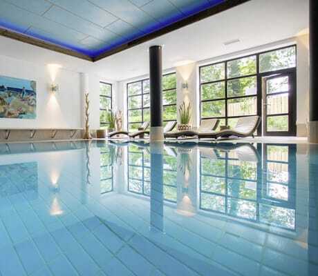 Indoorpool im Yachthotel Chiemsee mit großem Poolbild an der Stirnseite