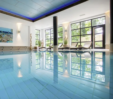 Indoorpool im Yachthotel Chiemsee mit großem Poolbild an der Stirnseite
