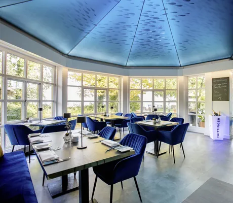 stylisches Restaurant im Yachthotel Chiemsee mit blauen Samtstühlen und blauer Decke mit Fischen