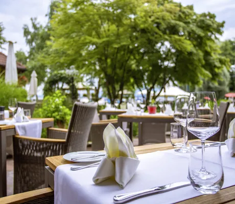 eingedeckte Tische auf der Terrasse des Yachthotel Chiemsee mit Blick auf den See