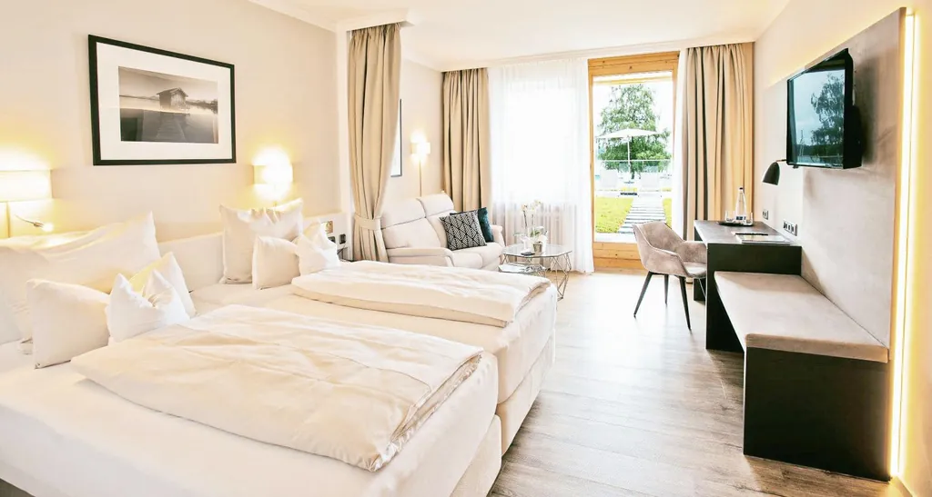 Zimmer im Yachthotel Chiemsee mit weißem Sofa und Blick auf Terrasse und See