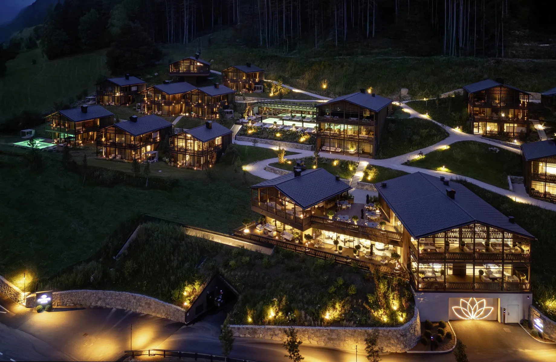 Gesamtansicht der beleuchteten Amonti Chalets von oben in der Nacht