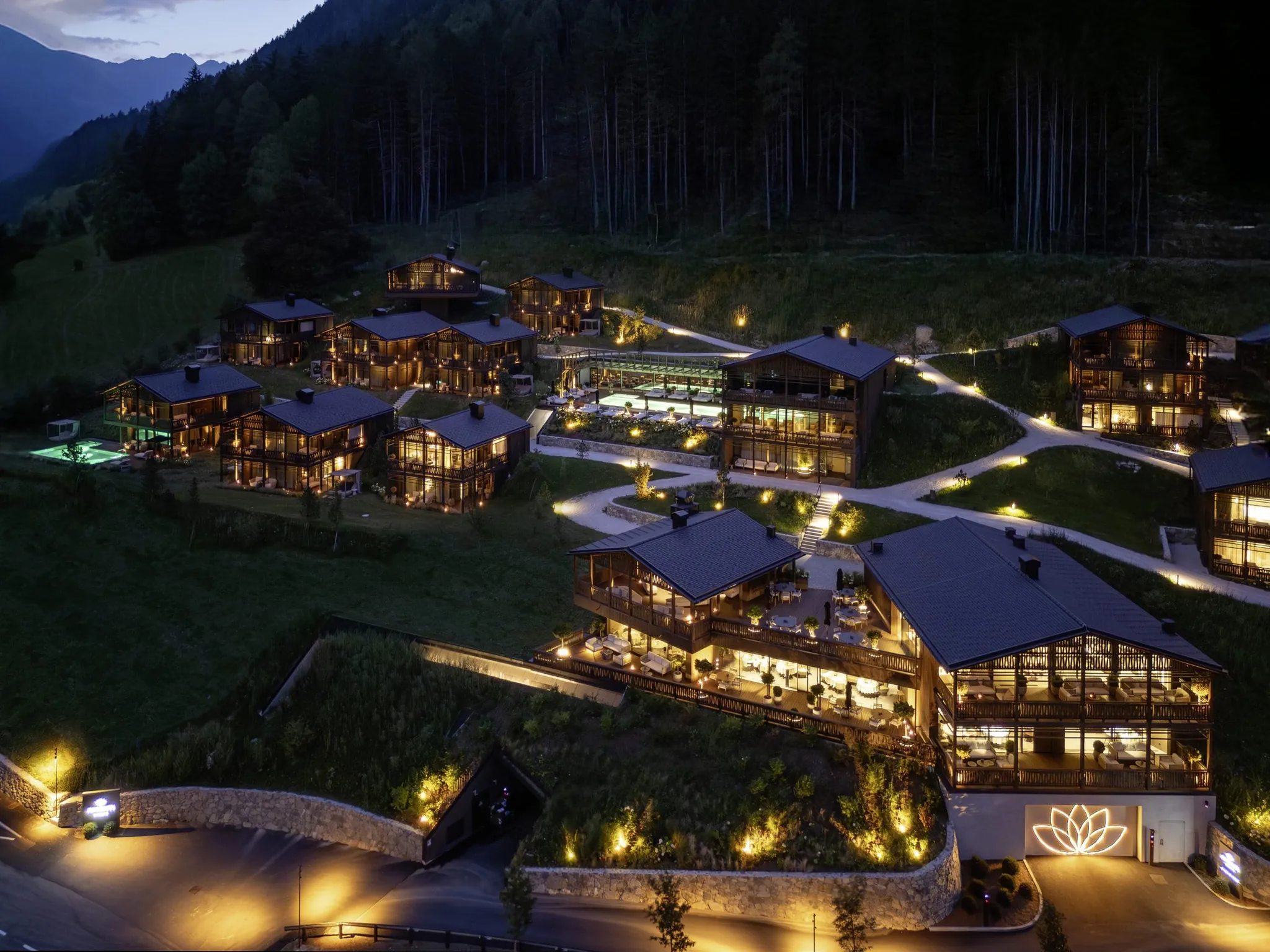 Gesamtansicht der beleuchteten Amonti Chalets von oben in der Nacht