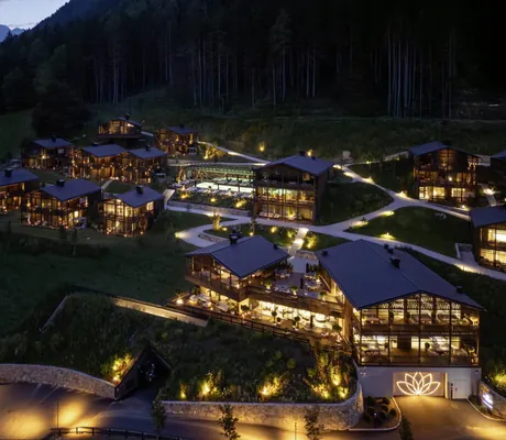 Gesamtansicht der beleuchteten Amonti Chalets von oben in der Nacht