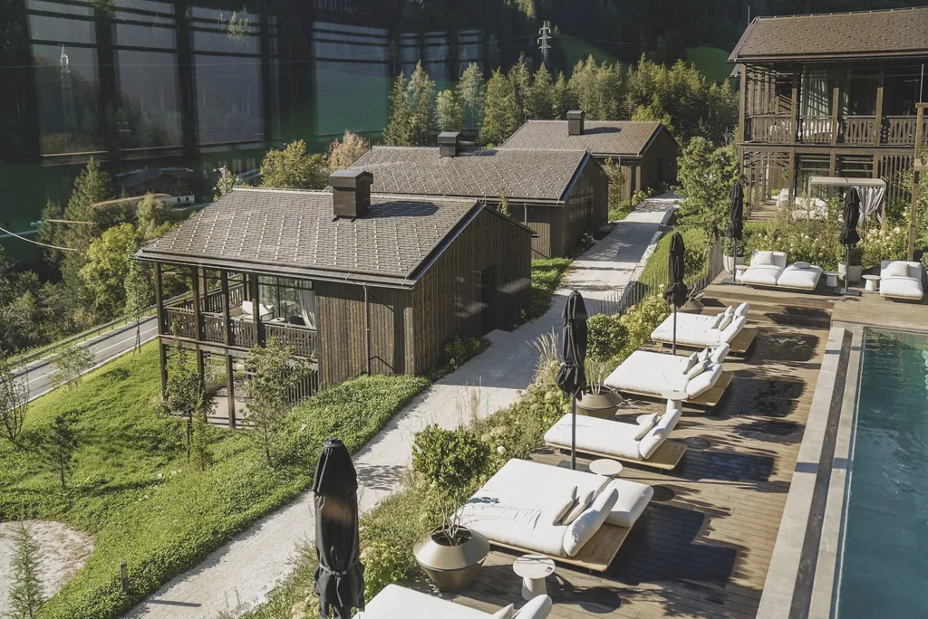 Blick von oben auf die weißen Polsterliegen am Outdoorpool neben den Amonti Chalets