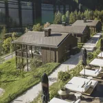 Blick von oben auf die weißen Polsterliegen am Outdoorpool neben den Amonti Chalets