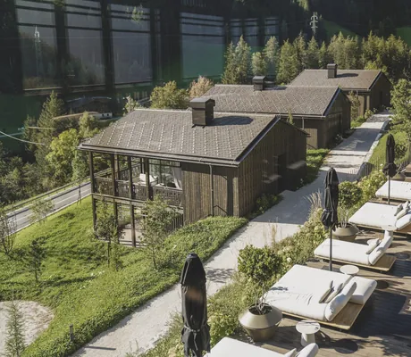 Blick von oben auf die weißen Polsterliegen am Outdoorpool neben den Amonti Chalets