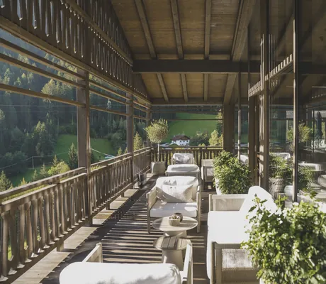 Balkon mit Holzbrüstung und weißen Polsterecken in den Amonti Chalets