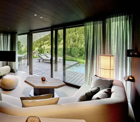 große Polsterecke am brennenden Kamin im Wohnzimmer der Amonti Chalets