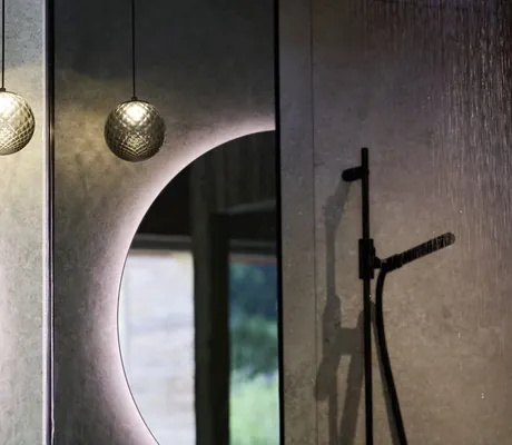 Runder beleuchteter Spiegel, kugelförmige Pendelleuchte und Regendusche mit rechteckiger Duschkopföffnung in den Ziegelberg Chalets
