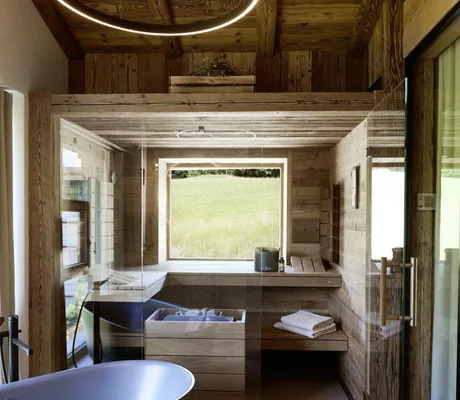 Bad in den Ziegelberg Chalets mit freistehender Badewanne, Sauna mit Blick ins Grüne und rundem Deckenlicht