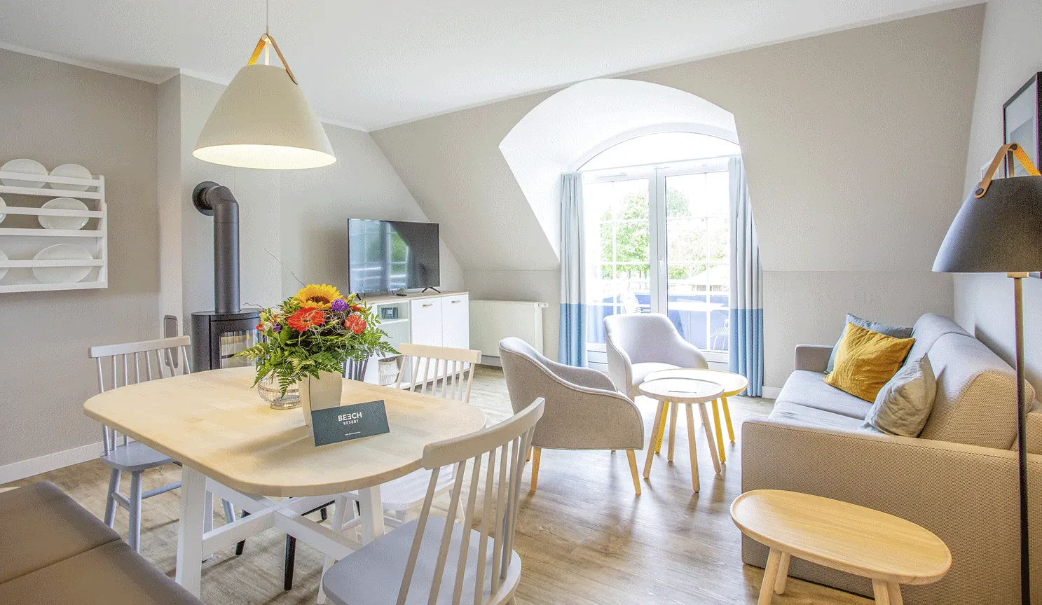 Wohnbereich im Appartement des BEECH Resort Fleesensee mit großem Fernseher und Schwedenofen