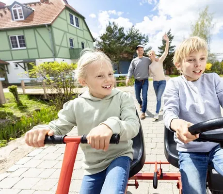 blondes Kinderpaar fährt auf Doppel-Kinderfahrzeug im BEECH Resort Fleesensee