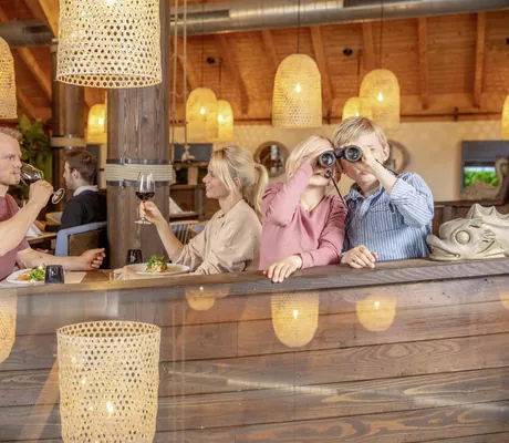 zwei Kinder schauen durch ein Fernglas im Restaurant des BEECH Resort Fleesensee