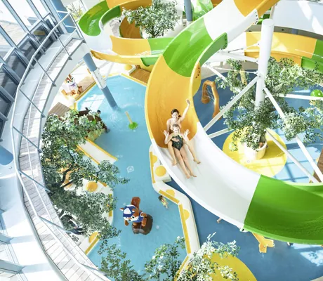 Frau mit Kind rutscht bunte Wasserrutsche im BEECH Resort Fleesensee hinunter