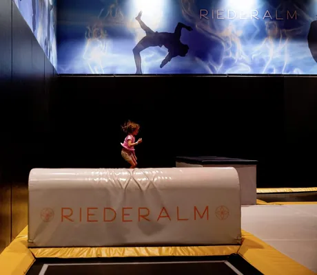 Mädchen springt auf einem Trampolin in der Trampolinhalle der Riederalm