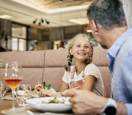 Mädchen mit Zöpfen sitzt mit Vater im Tuxerhof beim Frühstück