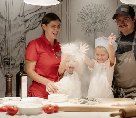 zwei Kinder in Kochoutfit backen mit ihren Eltern im Tuxerhof Pizza