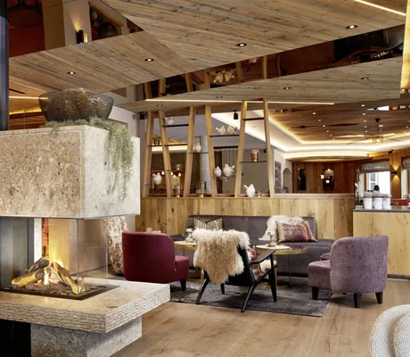 Lobby im Tuxerhof mit brennendem Kamin und Fellen über den Sesseln