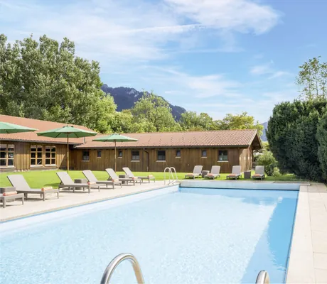 Outdoorpool des Hundesporthotel Wolf mit Blick auf die Hundescheune und Oberammergauer Berge