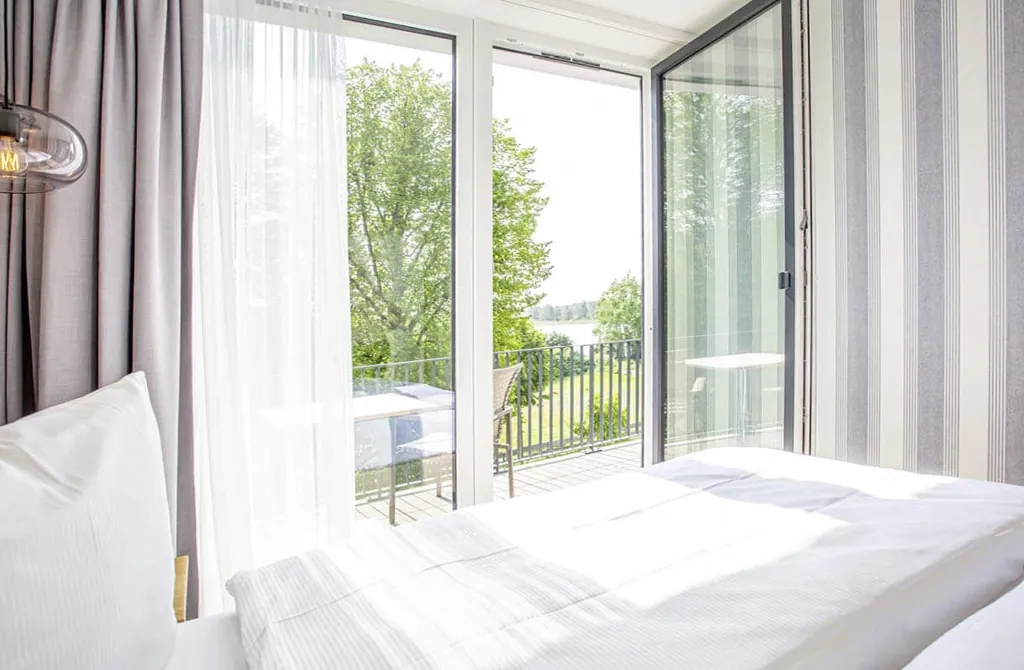 Blick vom Bett im Maremüritz Yachthafen Resort über den Balkon auf den See