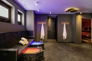 Moderner Wellnessbereich im Hotel Mischun mit zwei Fußbädern, Handtüchern an Haken und indirekter Beleuchtung in warmen Farben