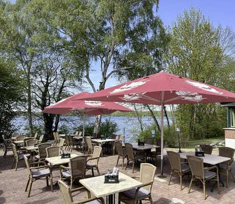 gastronomische Terrasse am See mit roten Sonnenschirmen im Seehotel Heidehof
