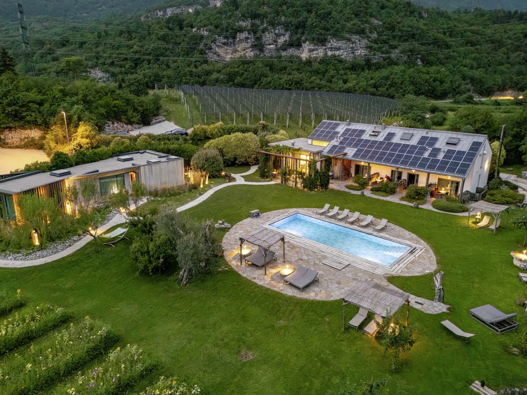 Luftaufnahme von dem in der Abenddämmerung beleuchteten Agritur La Dolce Mela mit Outdoorpool