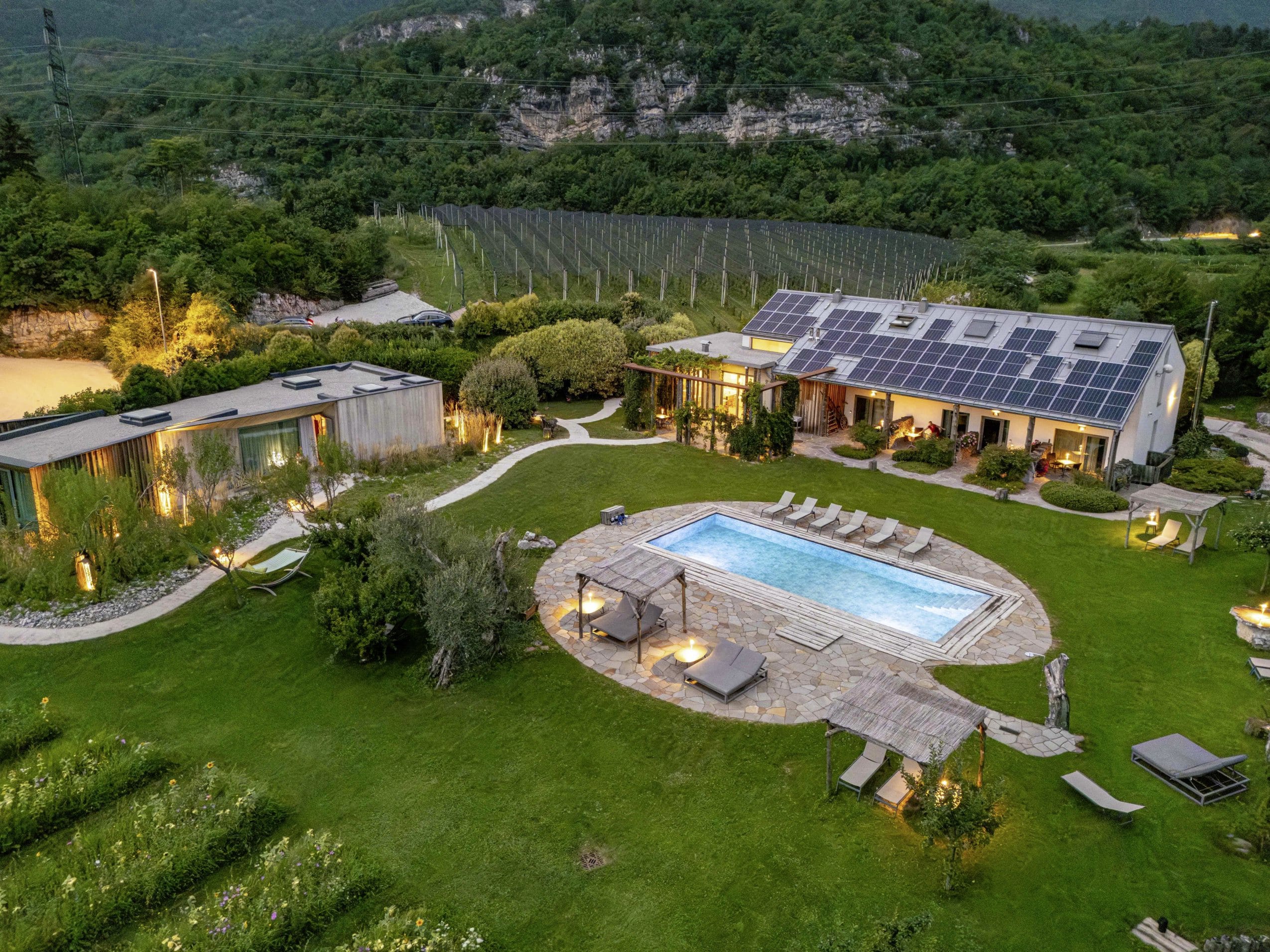 Luftaufnahme von dem in der Abenddämmerung beleuchteten Agritur La Dolce Mela mit Outdoorpool
