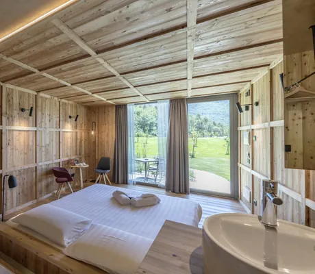 Zimmer mit Holzwänden, Doppelbett und Zugang zur Terrasse im Agritur La Dolce Mela