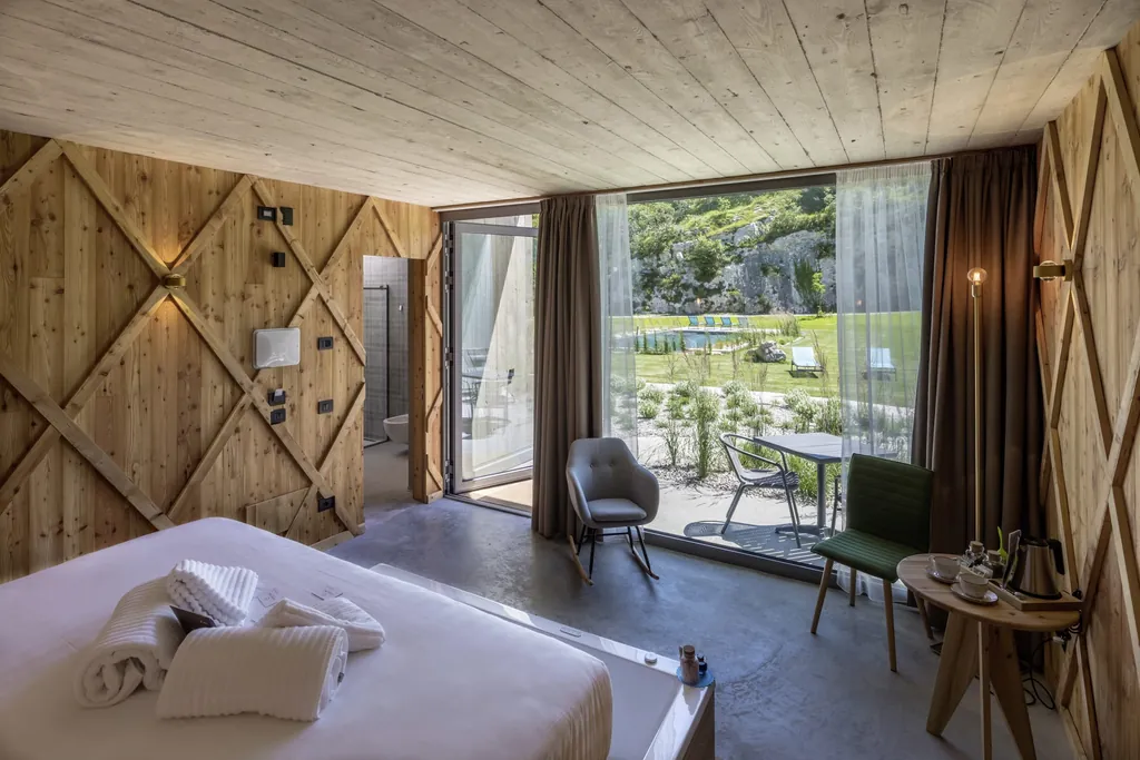 Zimmer komplett aus Holz und bodentiefen Fenstern, durch die man auf den Outdoorpool im Agritur La Dolce Mela sieht