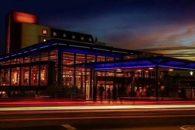 beleuchtete Außenansicht des Freizeit In bei Nacht mit verwischten Autolichtspuren