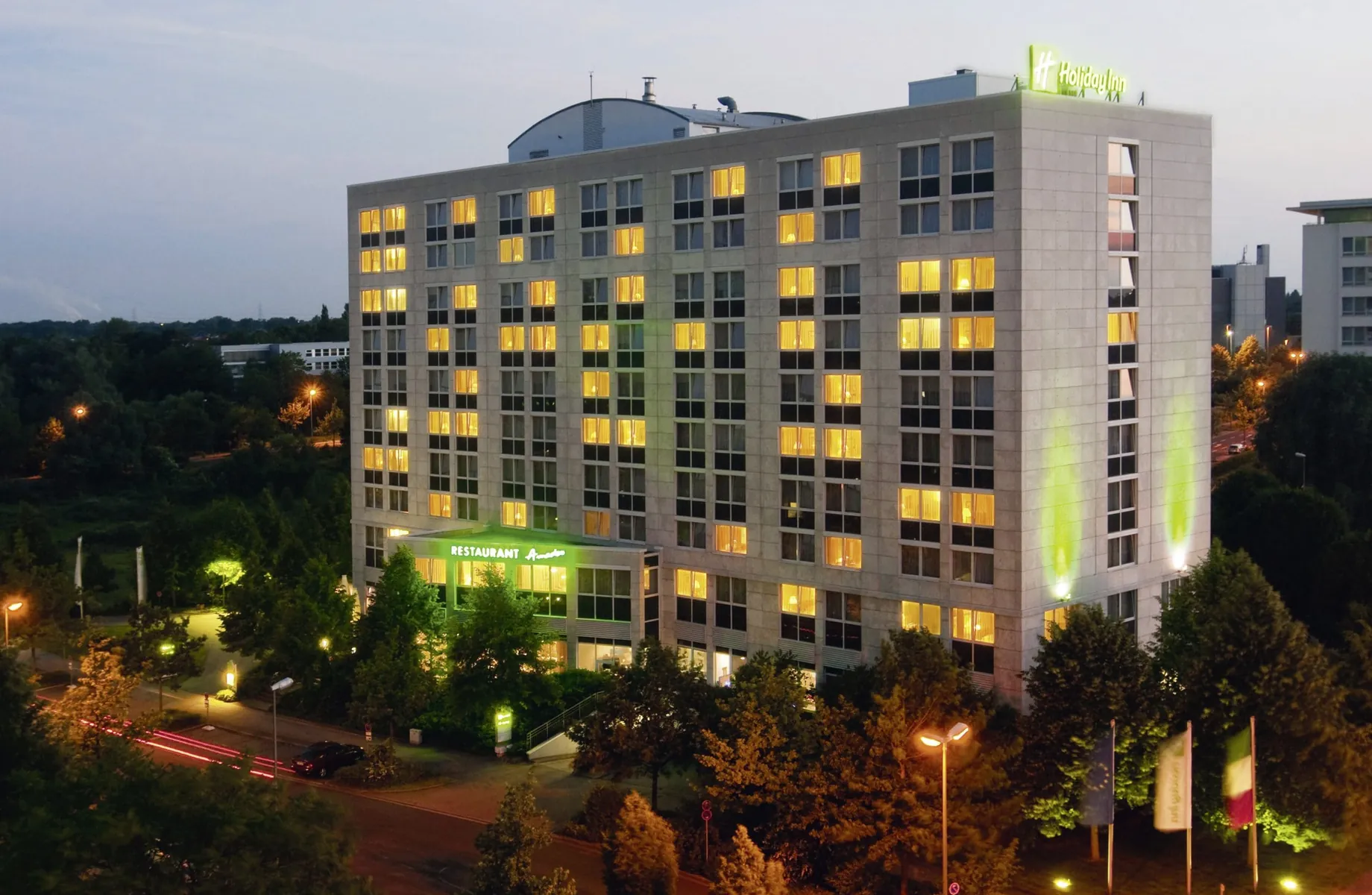 Außenansicht des Holiday Inn Neuss im Abendlicht mit beleuchtetem Logo
