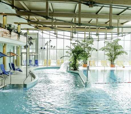 Schwimmhalle mit Holzdachkonstruktion und großen Pflanzenkübeln im Hotel am Vitalpark