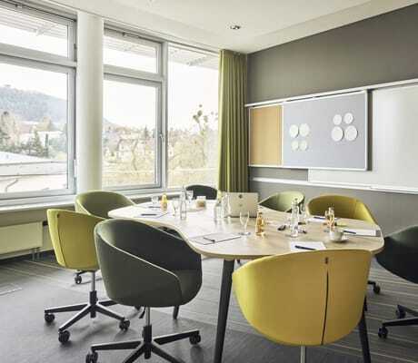 Besprechungsraum im Hotel am Vitalpark mit gelben und grünen Drehstühlen und Tafel