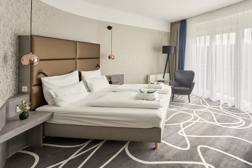Zimmer im Hotel am Vitalpark mit weißem Schlingenmuster im grauen Teppich und kupferfarbenen Lampen