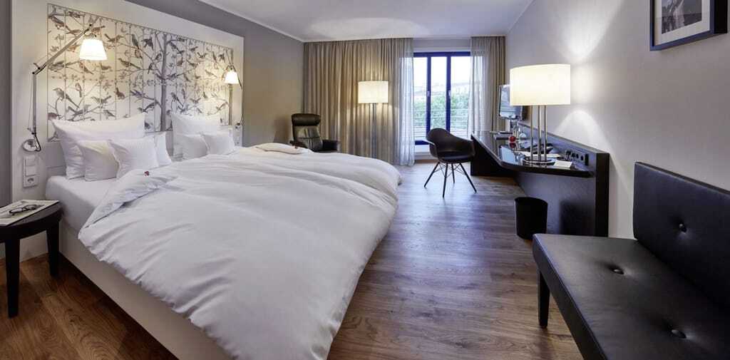 Doppelzimmer im Parkhotel Pforzheim mit schwarzer Lederbank und Vogeltapete am Bettkopf